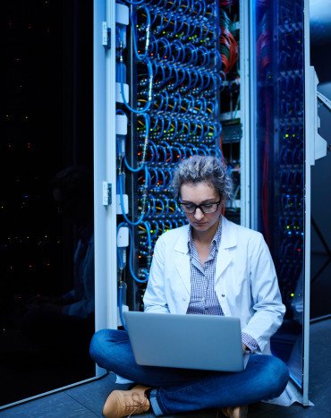 Woman using laptop while seated on floor.