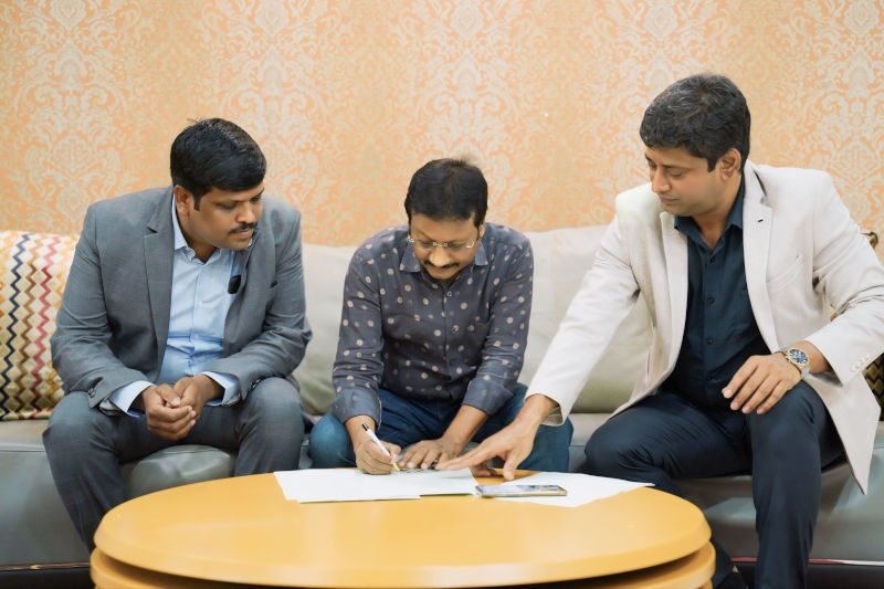 Three men signing papers at a table.